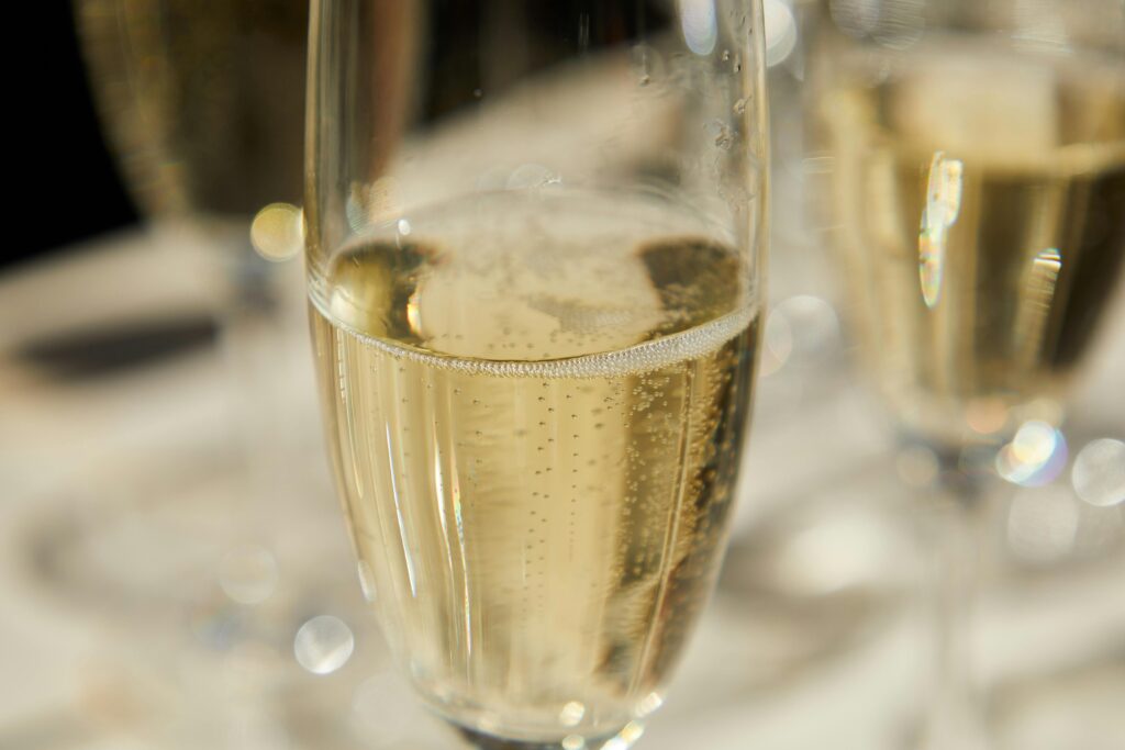Elegant close-up of sparkling wine in a tall glass with bubbles and bokeh effect.